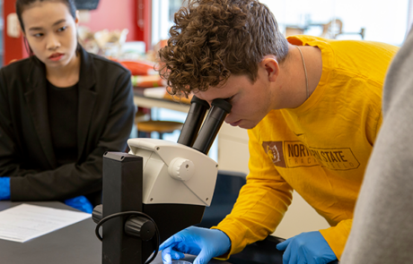 student looking into microscope